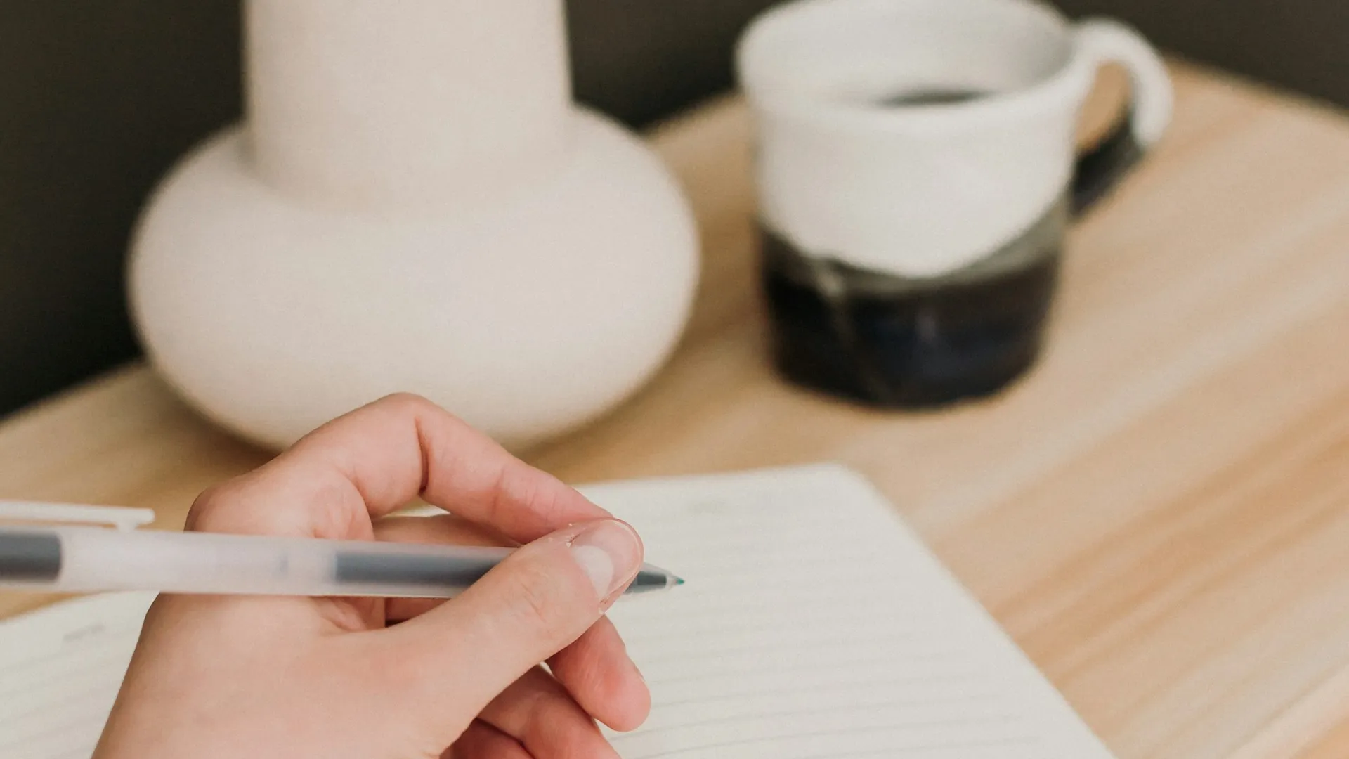Hand writing in a notebook with coffee and dried flowers