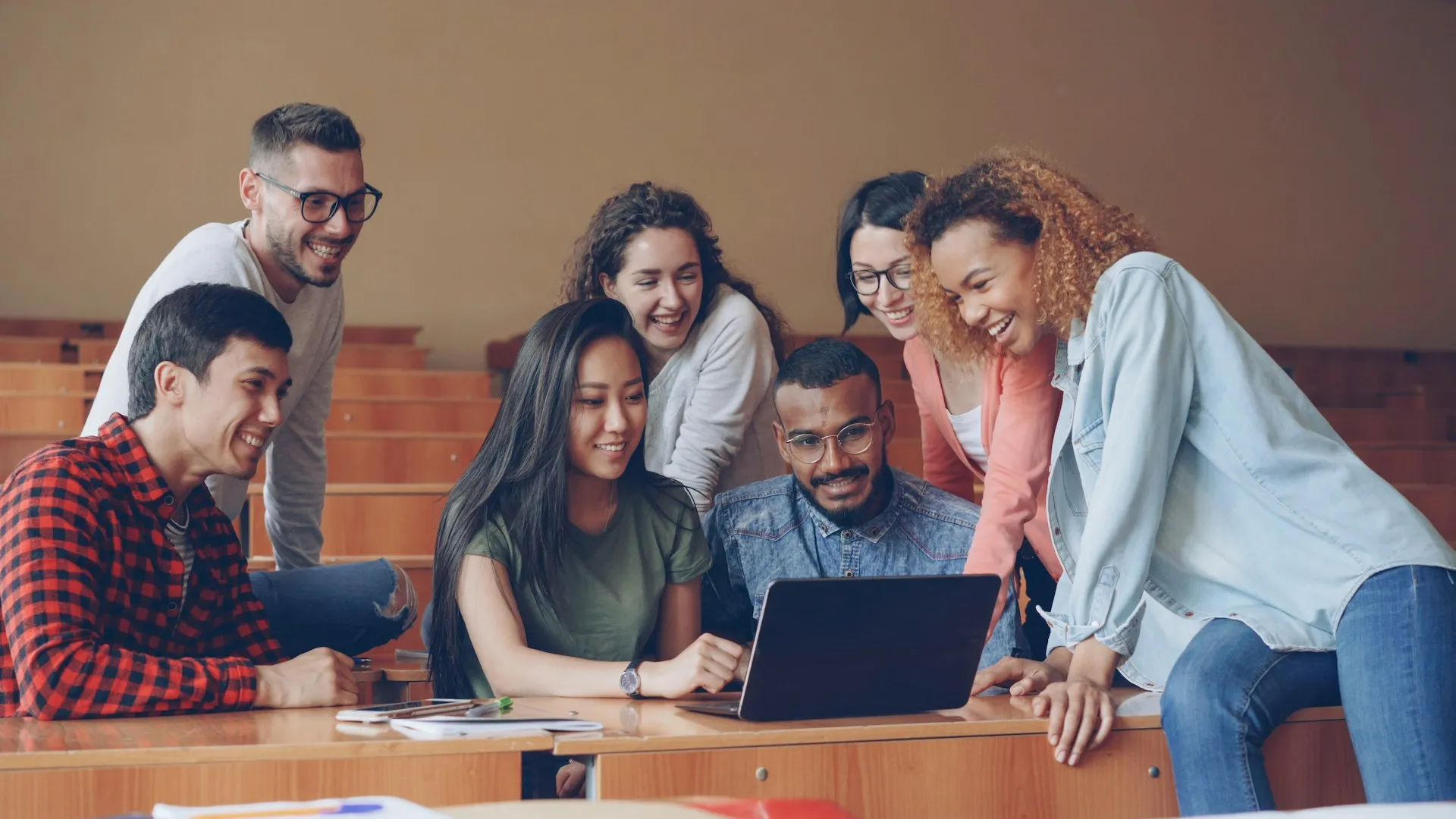 Diverse group of students gathered around a laptop