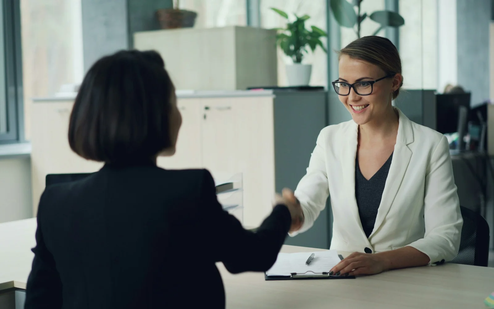 Two professionals shaking hands across a desk — ESL recruiter consultation