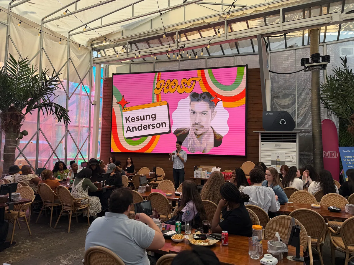 Kesung Anderson on stage at the Korvia Spring Party 2026 — HOST screen with his name displayed at Waikiki Beach Pocha, Itaewon