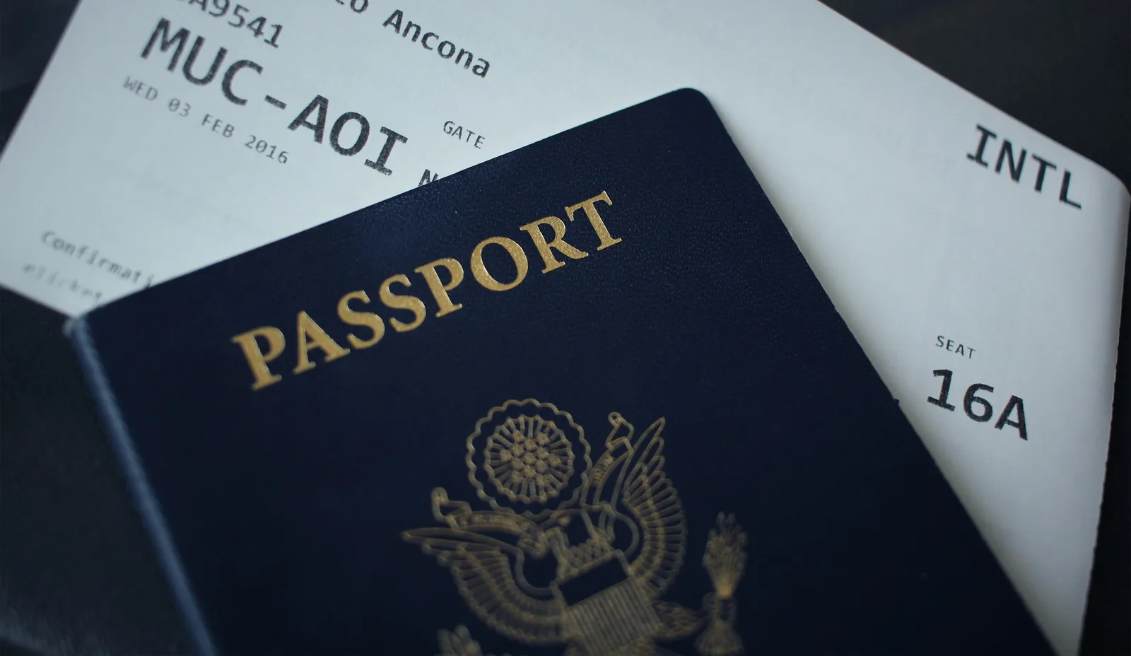 A passport booklet resting on a stack of white paper documents — applying for the E-2-2 visa at a Korean consulate